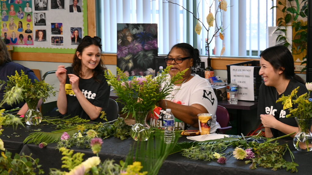 Volunteers work with a Deborah's Place resident on creating a floral arrangement